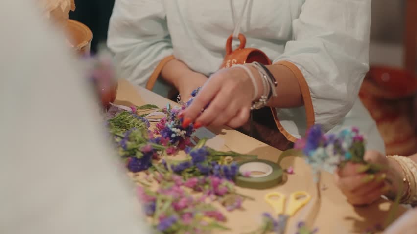People crafting floral arrangements with colorful flowers at a table, hands on creativity