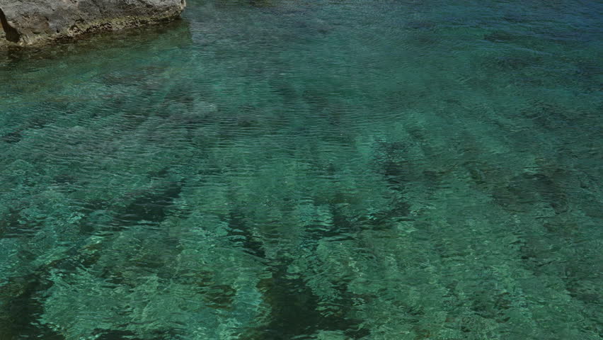 Crystal clear turquoise waters near rocky shore in torre dell