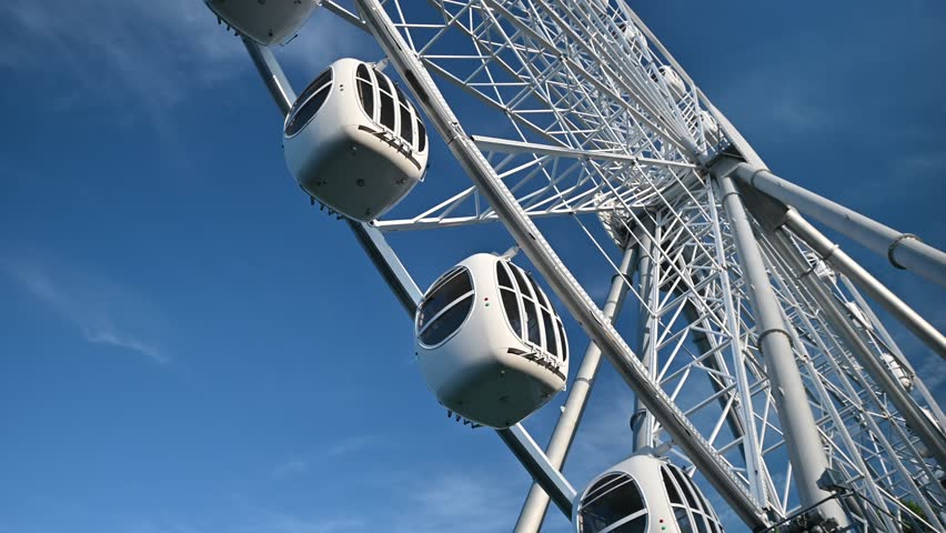 The attraction wheel rotates in the photo of the blue sky. An entertaining carousel on a hot summer day. Amusement park , spinning wheel on a blue sky background