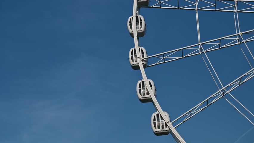 The attraction wheel rotates in the photo of the blue sky. An entertaining carousel on a hot summer day. Amusement park , spinning wheel on a blue sky background