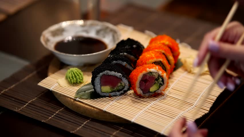 Chopsticks Take Japan Sushi In Japanese Restaurant. Traditional Sushi Maki Rolls With Tuna Philadelphia Cheese Avocado, Cucumber, Rice And Nori. Japanese Food Sushi Roll Uramaki, Nigiri And Hosomaki