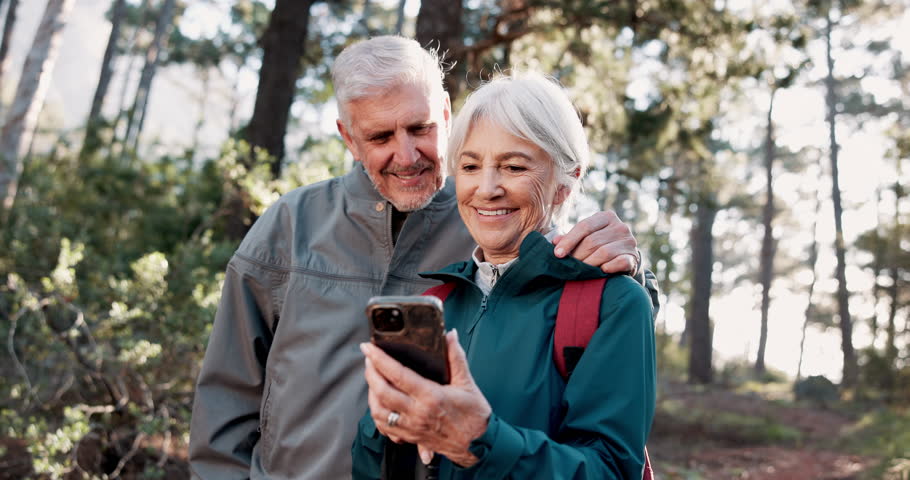 Phone, hiking or senior couple laughing in nature for connection, social media or streaming in forest. Norway, smile or happy people trekking in woods for funny meme comedy, travel and mobile app