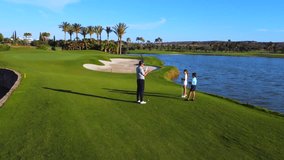 Male mature instructor teaching a girl how to play golf next to a boy in a luxury green gold course - Powered by Shutterstock - Get 15% off with code: PIKWIZARD15