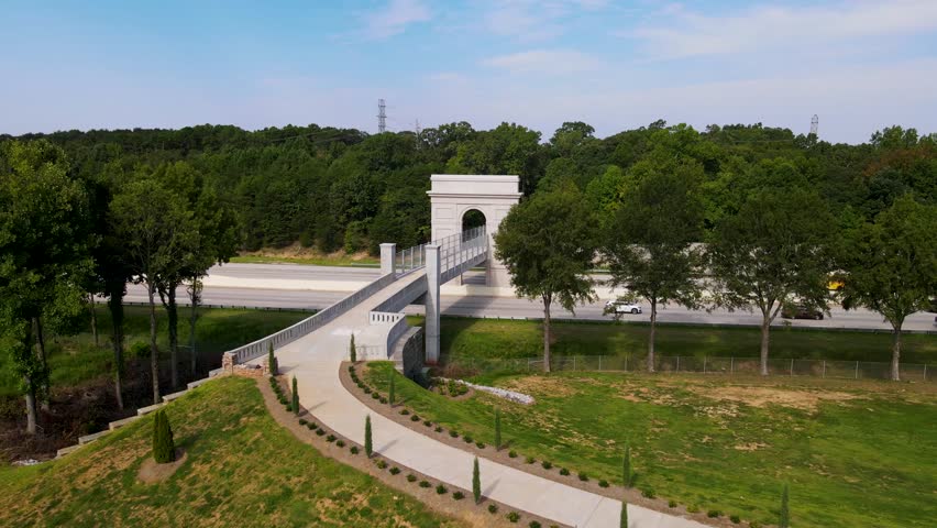 A modern walkway bridge over an interstate in Simpsonville, South Carolina. The bridge connects the Swamp Rabbit trail to Bridgeway Station, a modern castle-looking town center.