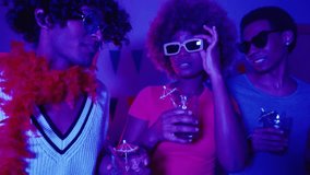 LGBTQIA friends, Latino gay couple and Black woman, dancing with colorful lights and mojitos at a house party - Powered by Shutterstock - Get 15% off with code: PIKWIZARD15