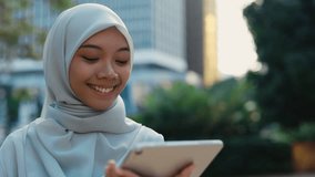 Islamic Girl Wearing Hijab Standing Outside and Using the Digital Device. Cute Muslim Lady in the Street Scrolling Pics in Social Media on the Tablet. People and Technology Concept - Powered by Shutterstock - Get 15% off with code: PIKWIZARD15