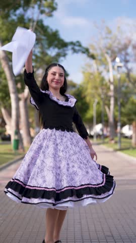 Young woman dressed as a Chilean huasa posing doing cueca steps, Fiestas Patrias concept 