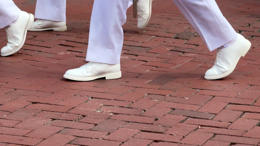 Navy Academy Brigade of Midshipmen march from Naval Academy through downtown Annapolis. Service men and women military college march focused on all white uniform in on cobblestone streets. Labor Day