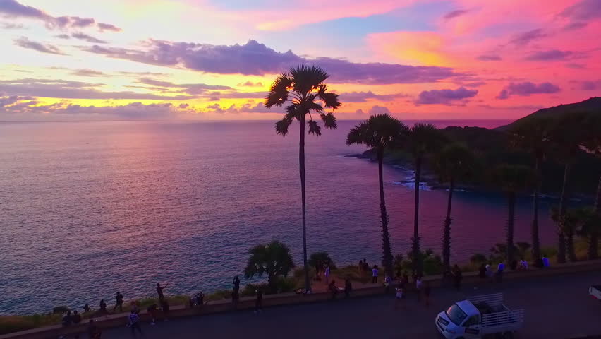 A stunning aerial view of a vibrant sunset casting a pink and purple glow over coastal hills and lush green landscapes creating a serene and captivating scene. sweet sky bove Promthep cape viewpoint