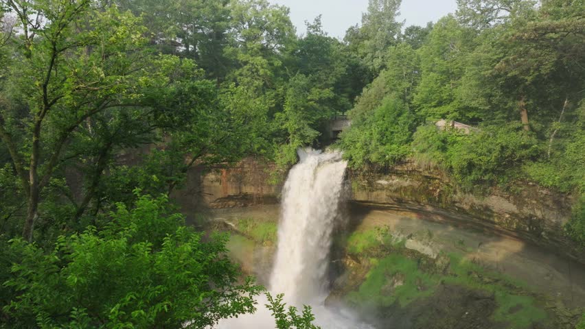 Forward moving aerial shot capturing Minnehaha Falls inside a forest of Minneapolis in Minnesota, USA.