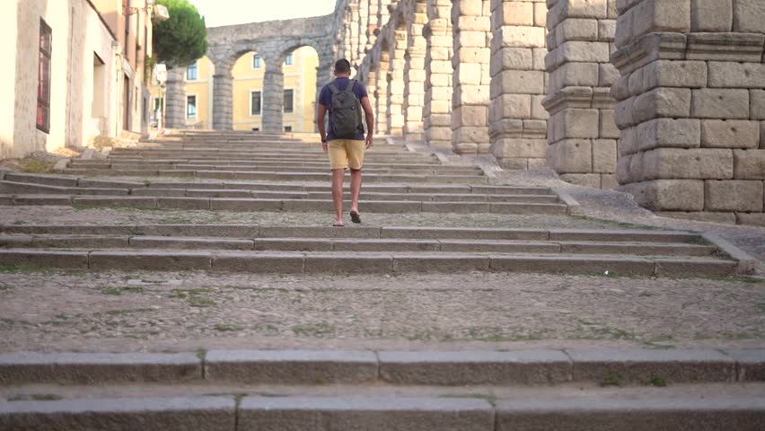 Aqueduct of Segovia visited by girl travelling to Spain walking arround this artichetectural structure which is considered as a world heritage.