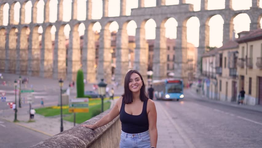 Aqueduct of Segovia visited by girl travelling to Spain walking arround this artichetectural structure which is considered as a world heritage.