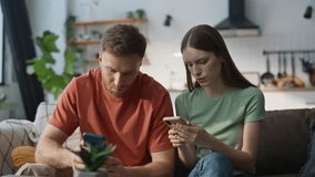 Concerned couple discussing message looking mobile phones in living room couch closeup. Serious spouses worried by bad news in cellphone sms. Puzzled woman talk to husband sitting home sofa together. - Powered by Shutterstock - Get 15% off with code: PIKWIZARD15