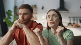 Emotional couple cheering sport game at apartment sofa closeup. Tensed husband wife watching TV football championship at home. Anxious woman and man reacting nervously on loss at living room couch. - Powered by Shutterstock - Get 15% off with code: PIKWIZARD15