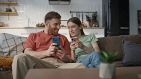 Cheerful couple relaxing on sofa living room looking mobile phones. Laughing woman discussing online purchase at smartphone with smiling man. Happy spouses talking together holding cellphones at home. - Powered by Shutterstock - Get 15% off with code: PIKWIZARD15