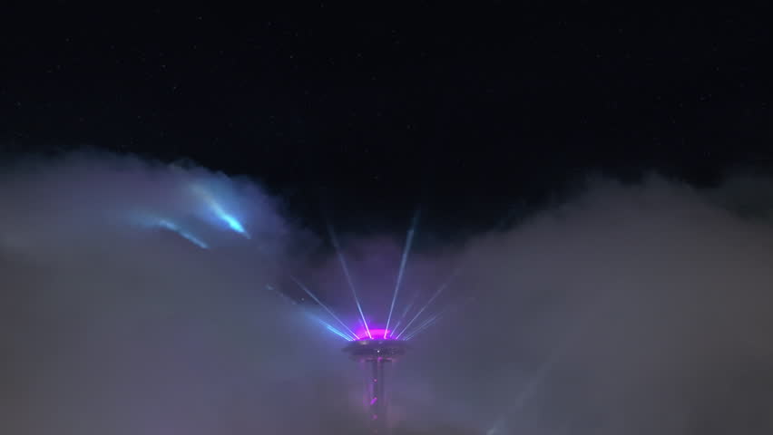 The Seattle Space Needle stands out against the night sky, bathed in colorful fireworks light, encapsulating the city