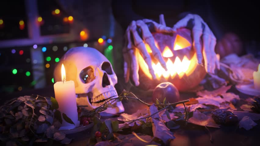 Witch hands touching pumpkins Jack Lantern, flashing inside, Halloween night spooky invitation background.