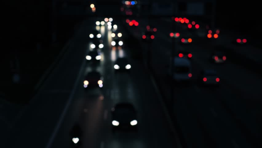 Fast motion driving cars on a german motorway, out of focus rush hour at night. Moving red and white light dots on a multi-lane road near Munich, Germany. There is an omnibus in the scene as well.