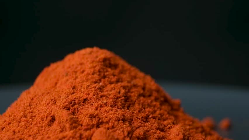 Ground paprika is a savory spice rotating on a black background.