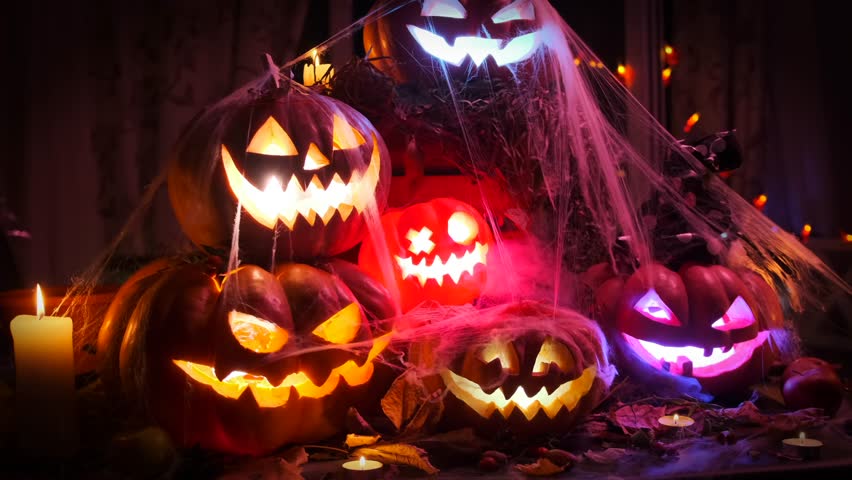 Carved Jack O'Lanterns with a creepy face among flickering candles and garlands, creative Halloween composition. - Powered by Shutterstock - Get 15% off with code: PIKWIZARD15