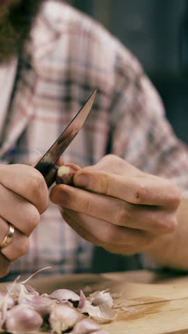Man preparing garlic cloves. Peeling off the peel with a knife