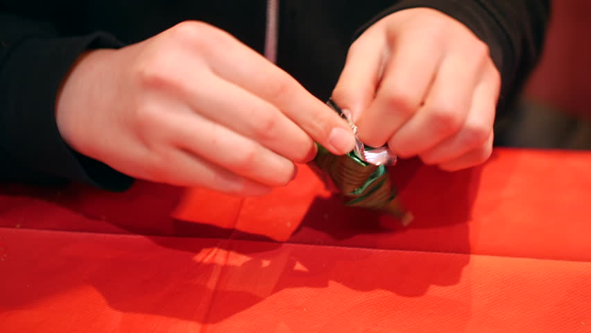 Close-up of hands carefully opening a fortune cookie on a bright red tablecloth. The anticipation and tradition associated with enjoying the chinese classic treat