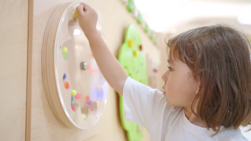 A Mixed Caucasian 4-Year-Old Girl Playing With a Spinning Ball Game in the Playroom - Close Up