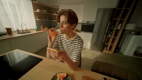 360 degree tracking shot of focused handsome young Caucasian man drinking orange juice while chatting on smartphone in kitchen of modern studio. Happy guy sitting at breakfast table. Cinematic - Powered by Shutterstock - Get 15% off with code: PIKWIZARD15