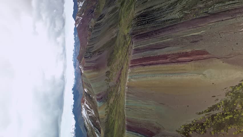 Vibrant rainbow-colored mountains in Palcoyo, Peru under a cloudy sky, aerial view