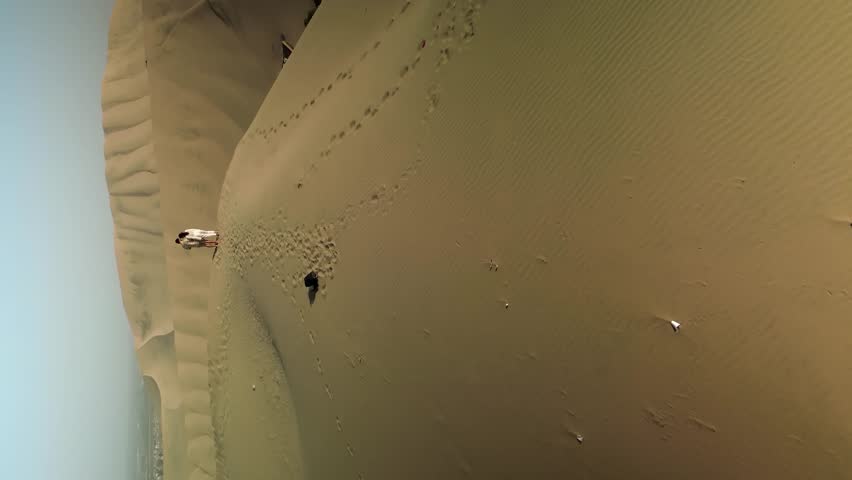 Romantic Couple on summit of sand dunes in Peru enjoying view on Huacachina Village. Sunny day in Famous City of
