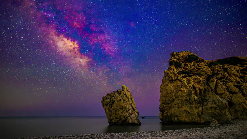 Timelapse view of colorful night sky stars milky way with huge rocks in foreground.