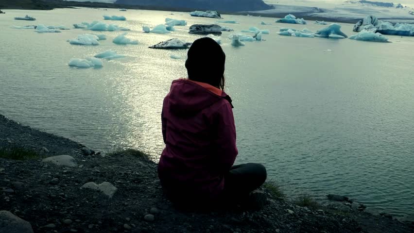 Young lady are doing yoga in summer sunset with sea background. A girl performing yoga in front of the sea on sunset. Concept of harmony with nature.