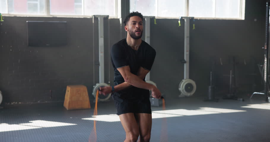 Exercise, fitness and jump rope with man in gym for training, muscle connection and workout. Health, strong and sports athlete with male person and skipping for energy, cardio and strength movement