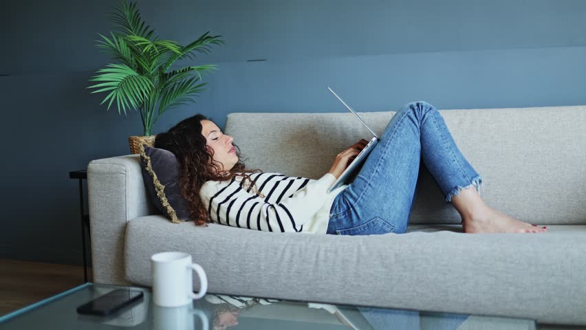 Woman closing her laptop at home, enjoying a moment of relaxation on her sofa after a productive workday   Woman ending working day closing laptop at home