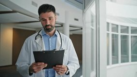 Serious therapist looking diagnosis clipboard. Closeup upset doctor walking hallway contemplating treatment. Focused healthcare expert checking patient chart in hospital. Thoughtful man in white coat - Powered by Shutterstock - Get 15% off with code: PIKWIZARD15