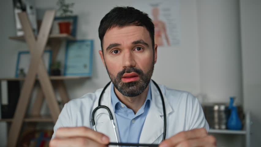 Healthcare worker communicating web conference closeup. Smiling man consulting patient online discussing diagnosis treatment on video call. Pov joyful doctor physician looking camera talking in clinic