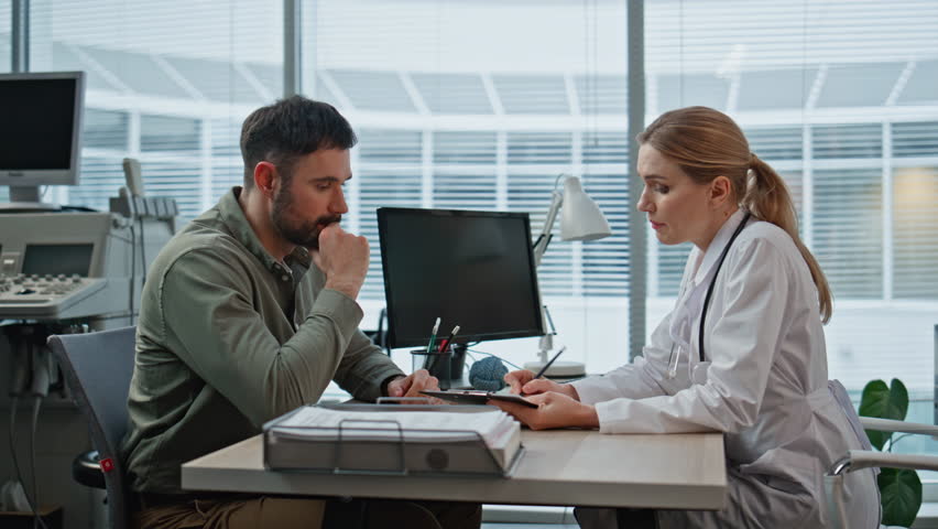 Doctor providing medical advice to clinic patient. Therapist discuss treatment options writing prescription during insurance appointment. Smiling focused practitioner talking man consulting on disease - Powered by Shutterstock - Get 15% off with code: PIKWIZARD15