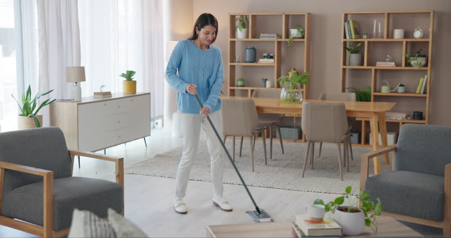 Woman, dancing or sweeping to clean home with broom for floor, ground or hygiene in living room. Girl, person or happy cleaner with spring cleaning music for working to stop dust, dirt or germs