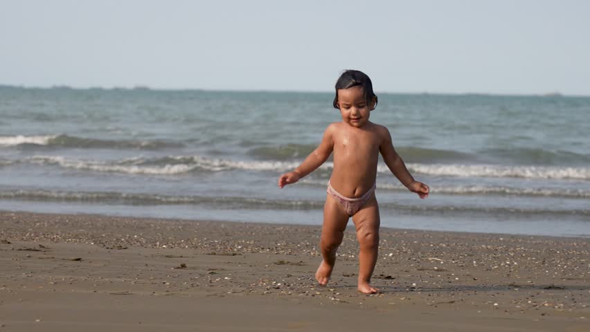 Cute baby girl walking on sandy beach. Little girl playing at beach enjoyin..