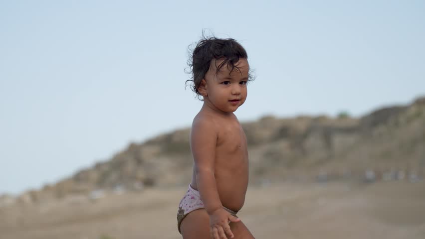 Cute baby girl walking on sandy beach. Little girl playing at beach enjoyin..