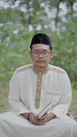 A muslim is reading quran in the forest