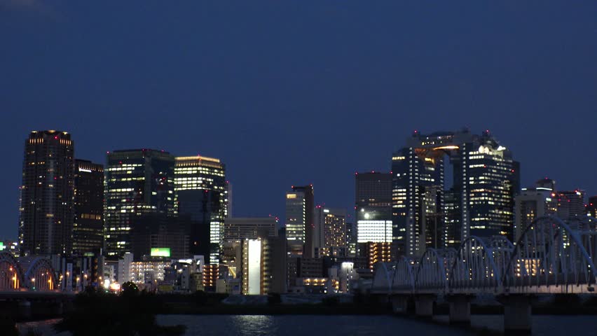 OSAKA, JAPAN - JUNE 2024 : View of buildings around Osaka station, bridge and Yodogawa river. Time lapse shot at night.