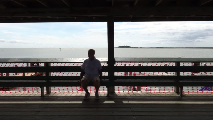 Crisfield, Maryland, USA A man walks on the City Dock in the downtown along the Chesapeake Bay and US flags. 