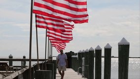Crisfield, Maryland, USA A man walks on a pier on the Chesapeake Bay shore with American flags flying in the wind.  - Powered by Shutterstock - Get 15% off with code: PIKWIZARD15