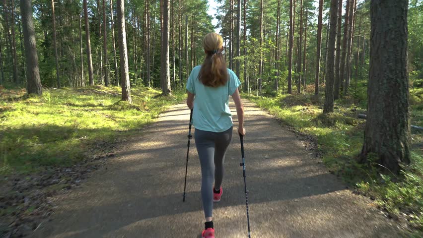 Active woman doing Nordic walking in a national park in Finland, doing sports in the park, staying fit by exercising