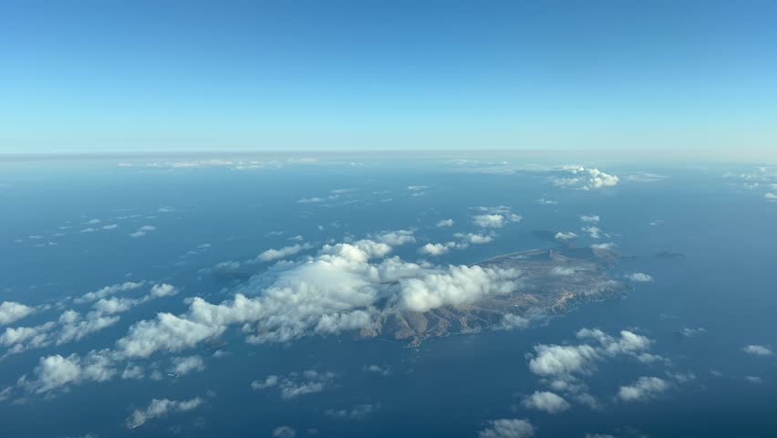 Aerial view of Porto Santo Island (Portugal). Aerial footage taken from an airplane cockpit flying bound to Madeira. The island and airport runway is partially covered by some low clouds. Daylight 4K