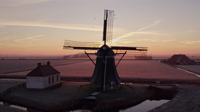 Aerial view of colourful windmill at sunrise in meadow, Tjerkwerd, Friesland, Netherlands.