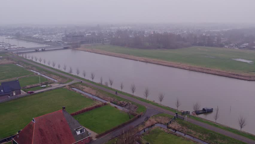 Aerial view of misty river and wetland with man on bicycle, Lemmer, Friesland, Netherlands.