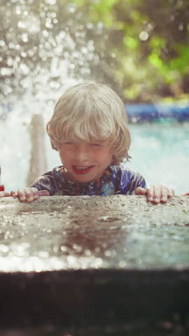 A close-up shot focuses on a young boy smiling while performing flutter kicks, splashing water in the pool