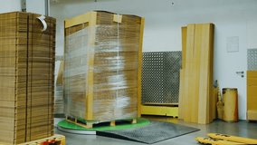 Folded cardboard boxes are packed for shipment in plastic film by a special machine. Modern cardboard factory, wrapping a pallet of cargo with cardboard in polyethylene film. Packing cargo, shipment - Powered by Shutterstock - Get 15% off with code: PIKWIZARD15